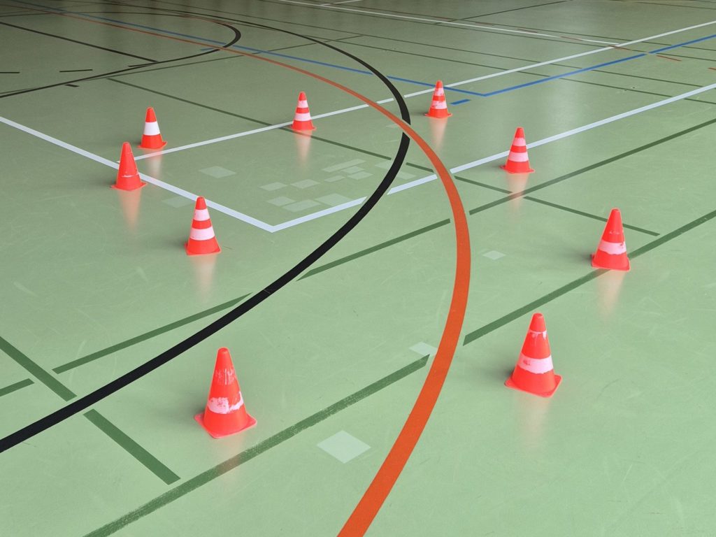 Salle de gymnastique après la réparation des déchirures du sol en résine, zones traitées protégées par des cônes pendant le séchage