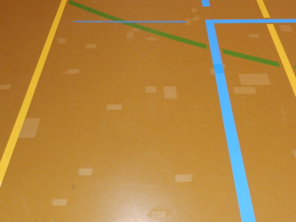 Sol sportif en résine après réparation, fissures traitées entre les lignes de jeu d'une salle de gymnastique