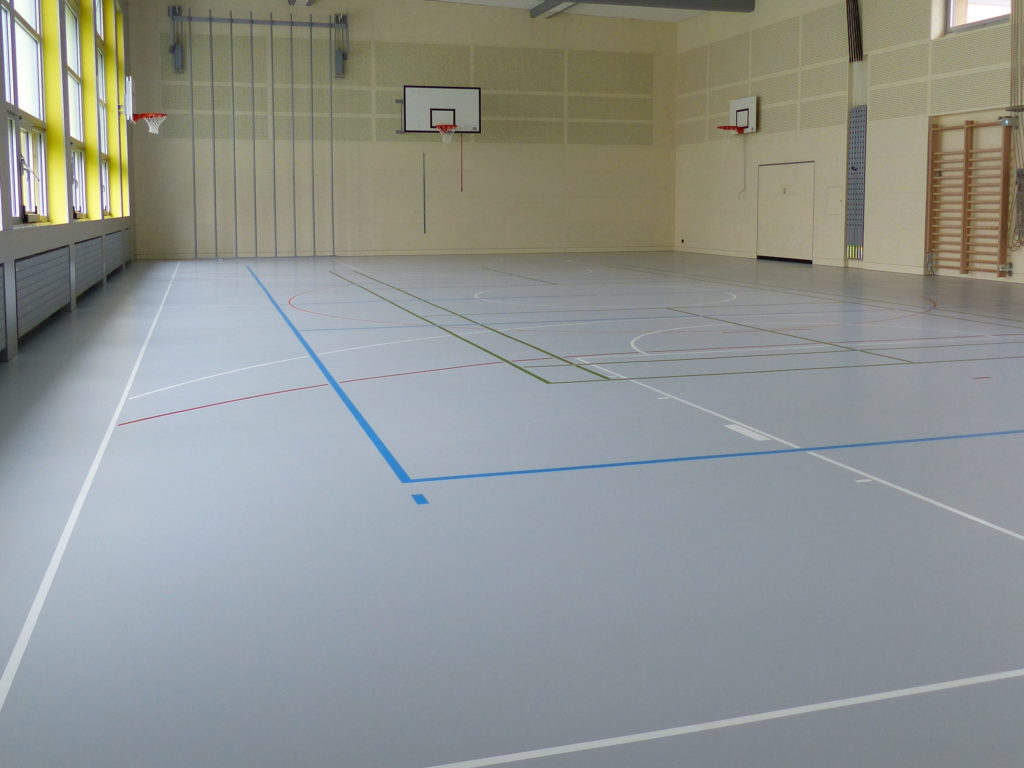 Salle de gymnastique avec un sol sportif en résine gris clair sur plancher souple et un marquage multisport