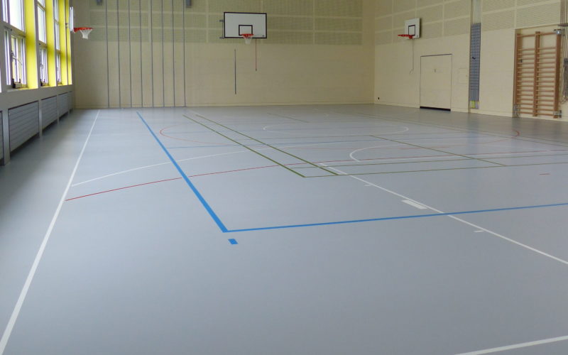 Salle de gymnastique avec un sol sportif en résine gris clair sur plancher souple et un marquage multisport