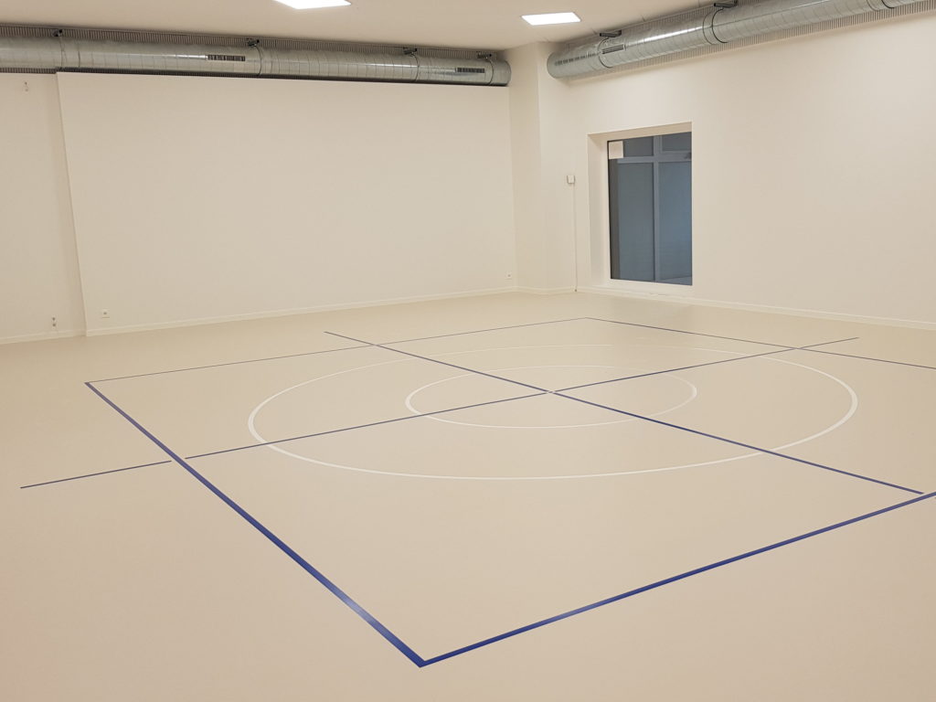 Salle de rythmique avec un nouveau sol sportif souple en résine, un marquage bleu et deux cercles blancs
