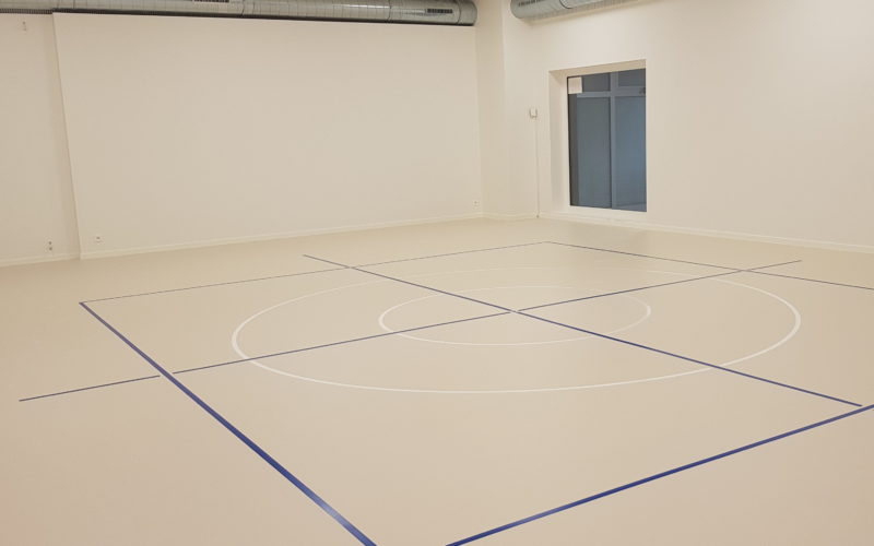 Salle de rythmique avec un nouveau sol sportif souple en résine, un marquage bleu et deux cercles blancs