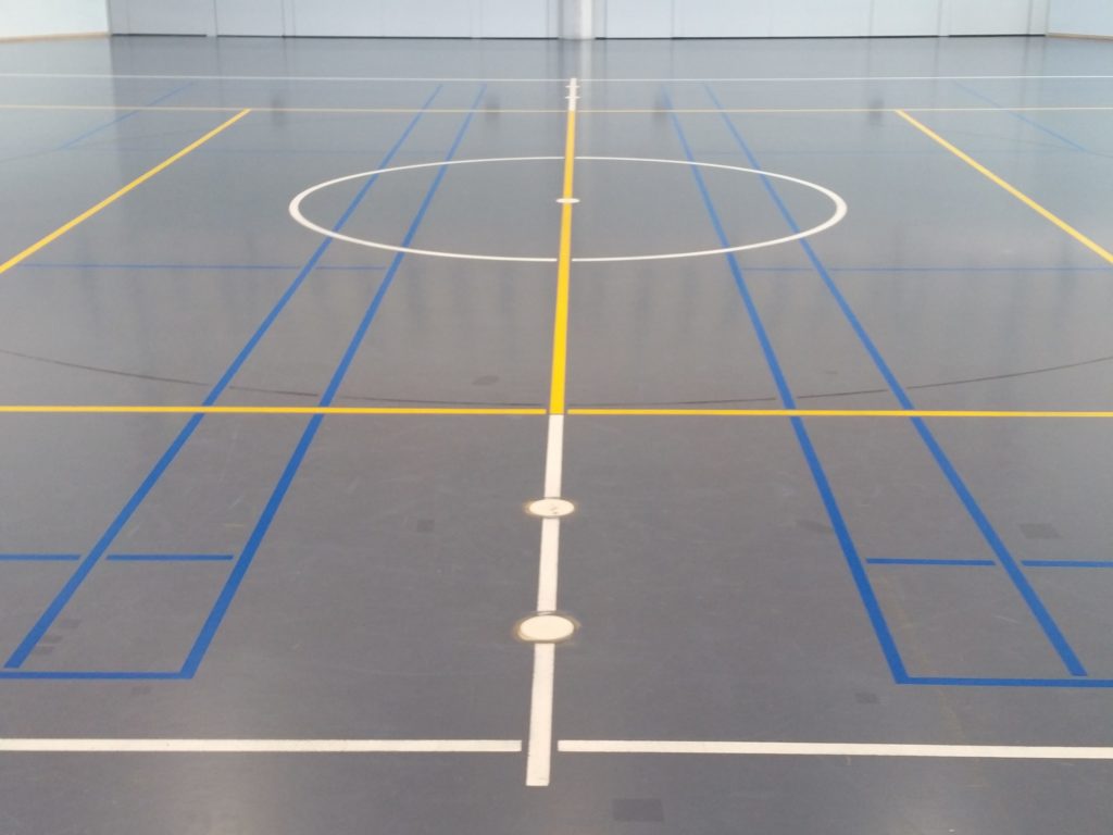 Salle de sport après remarquage, lignes de badminton bleu ciel nettement lisibles sur le sol bleu
