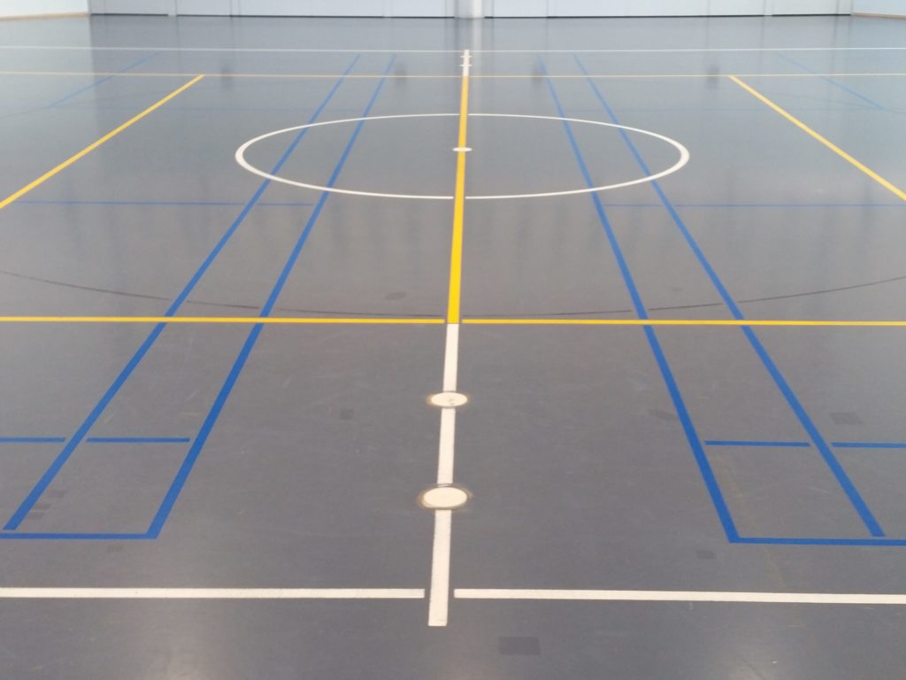 Salle de sport après remarquage, lignes de badminton bleu ciel nettement lisibles sur le sol bleu