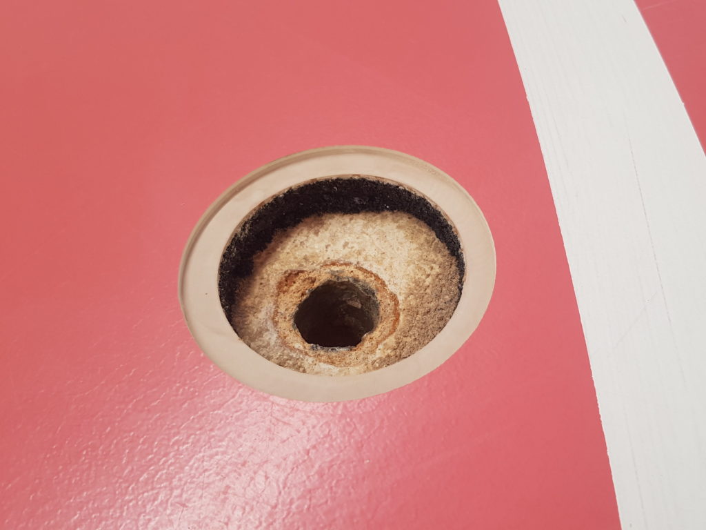 Trou de carottage dans un sol sportif, revêtement, sous-couche et support visibles en coupe