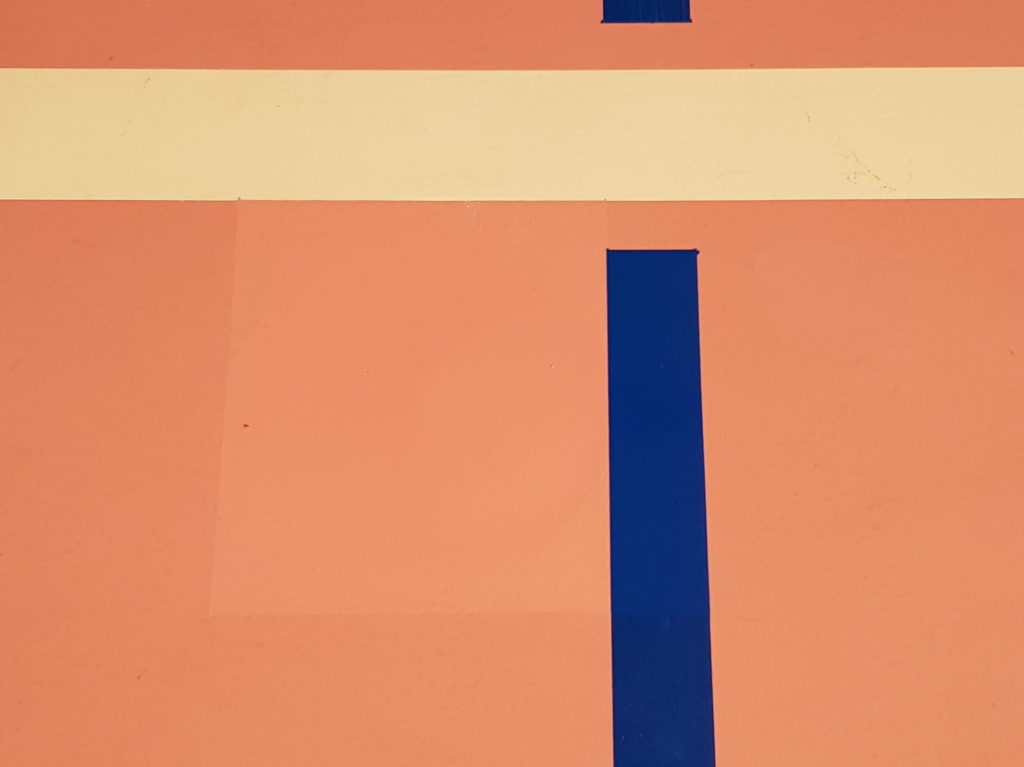 Trou de carottage refermé et repeint près d'une ligne de jeu bleue, à peine visible dans le revêtement