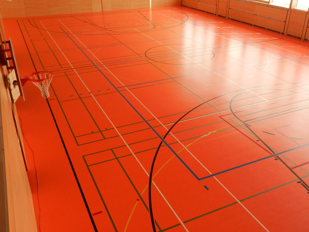 Vue d'ensemble d'une salle de sport avec quatre terrains de badminton marqués