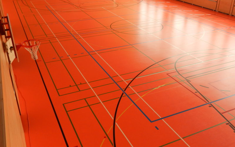 Vue d'ensemble d'une salle de sport avec quatre terrains de badminton marqués
