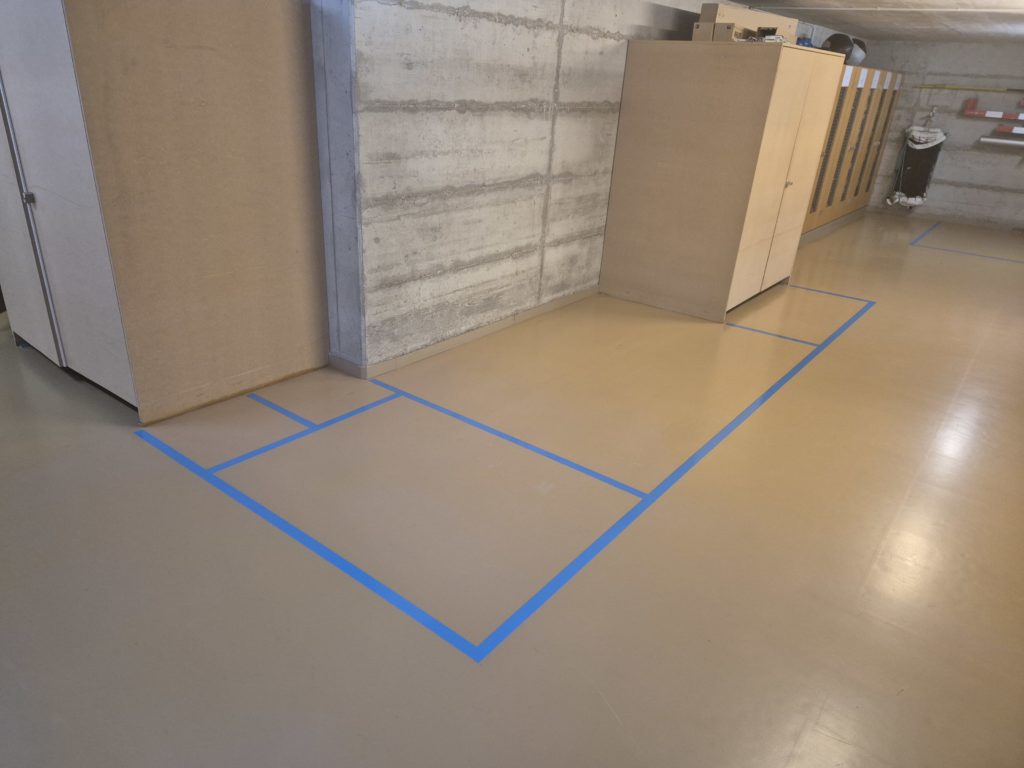 Zones de rangement marquées en bleu devant les armoires d'un local à engins