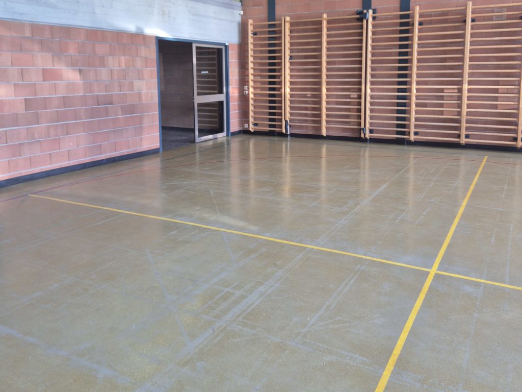 Ancien revêtement de sol d'une salle de rythmique, craquelé et usé, avant son remplacement par un sol sportif en résine