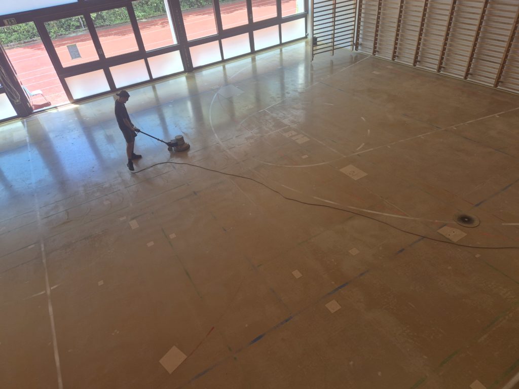 Dépolissage du sol sportif à la monobrosse pour dégraisser la surface et préparer l'accroche de la peinture.