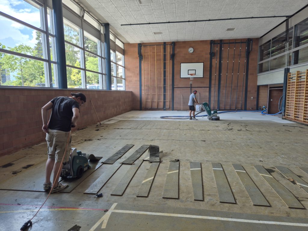 Dépose de l'ancien lino-liège d'une salle de gymnastique en lanières à la décolleuse, chape mise à nu et surfacée