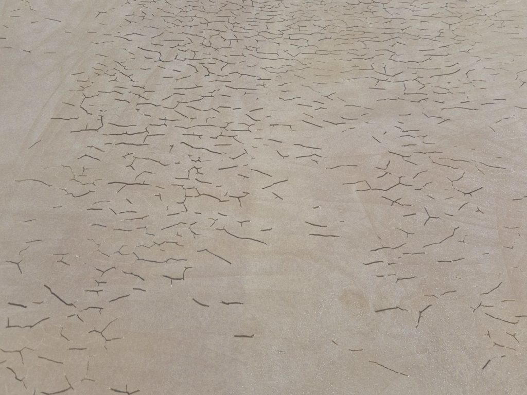 Gros plan sur un réseau de fissures dans un sol sportif en résine PU, avant réparation.