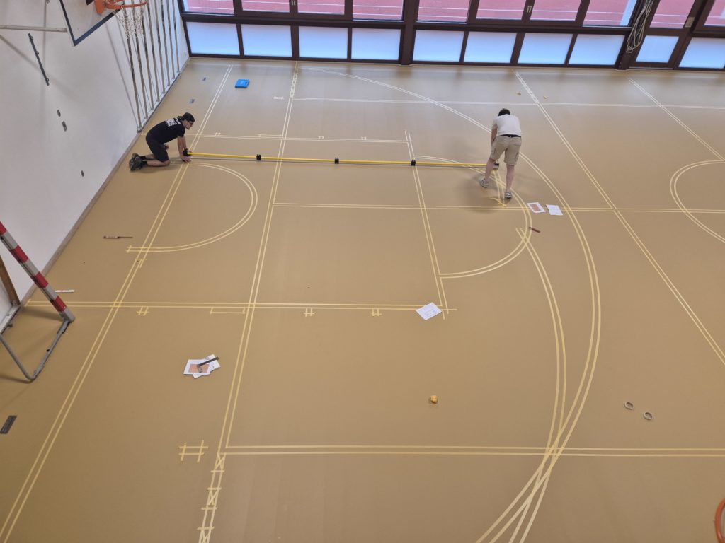 Implantation des lignes de jeu au scotch avec une barre de traçage, vue d'en haut.