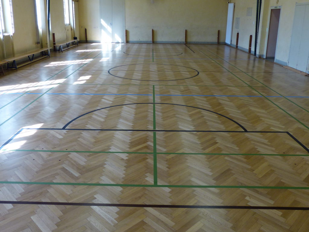 Parquet en chêne en bâtons rompus après ponçage et vitrification, avec les lignes de jeu retracées.