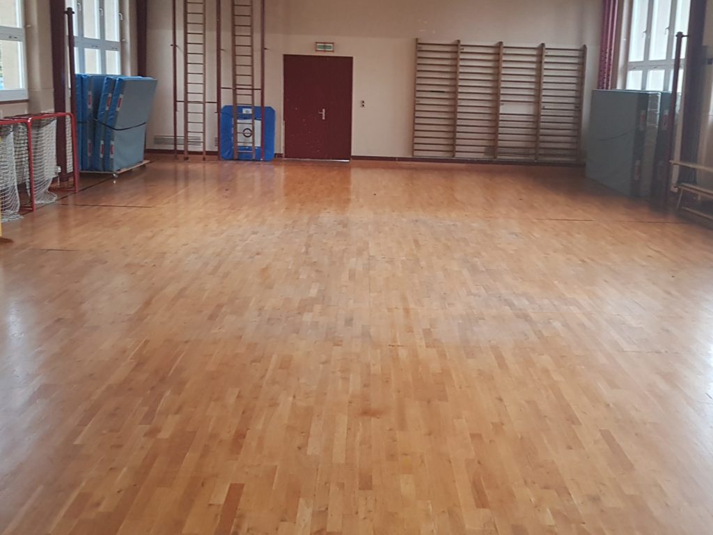 Parquet sportif en chêne avant rénovation : vitrification jaunie et lignes de jeu presque effacées.