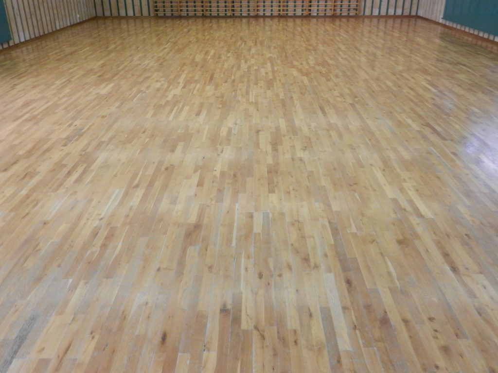 Parquet sportif en chêne avant rénovation, vitrification vieillie et usée sur toute la salle.