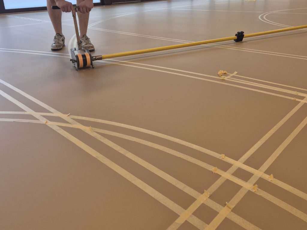 Pose du scotch au dérouleur le long de la barre de traçage pour délimiter une ligne de jeu.