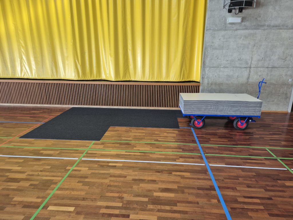 Protection d'un sol sportif : tapis de protection posé sur le parquet devant la scène, pour les manifestations