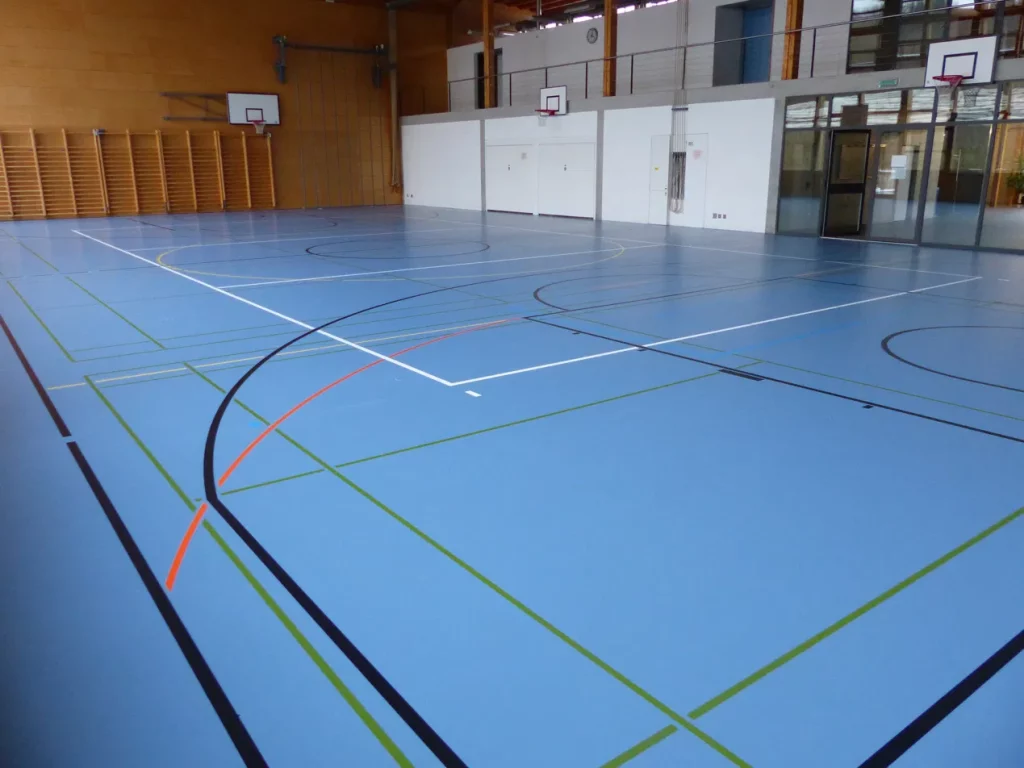 Rénovation de surface d'un sol sportif après des taches de nettoyage : salle à l'aspect d'un sol neuf