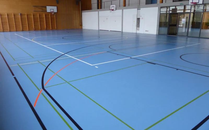 Rénovation de surface d'un sol sportif après des taches de nettoyage : salle à l'aspect d'un sol neuf
