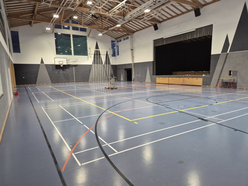 Salle polyvalente rendue aux utilisateurs après la remise en état d'un sol sportif à souplesse combinée à la suite d'une fuite d'eau
