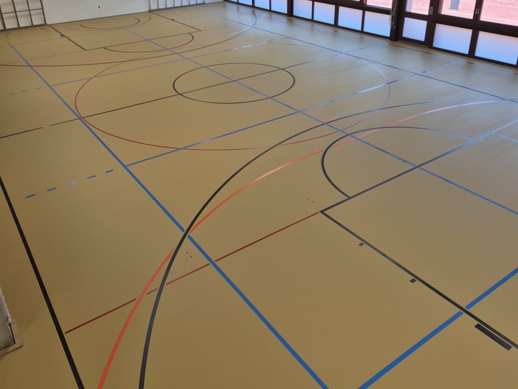 Sol sportif après la rénovation de surface : fissures réparées, deux couches de peinture et marquage refait.