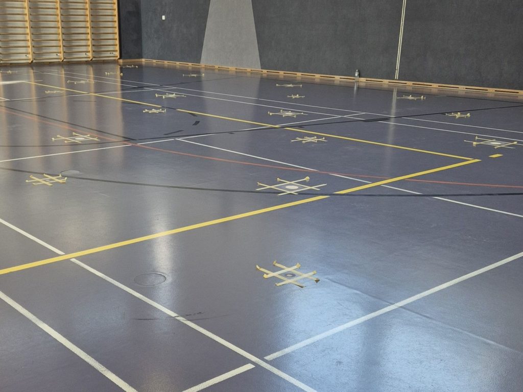 La même salle après la réparation : percements refermés, revêtement et lignes de jeu conservés