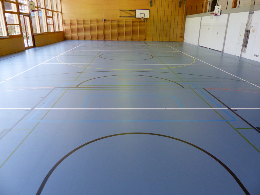 Le même sol sportif après rénovation de surface : teinte uniforme et nouveau marquage