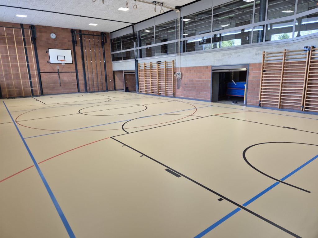 Salle de gymnastique équipée d'un nouveau sol sportif ProtecSport SP 40 beige, avec un marquage noir, bleu et rouge