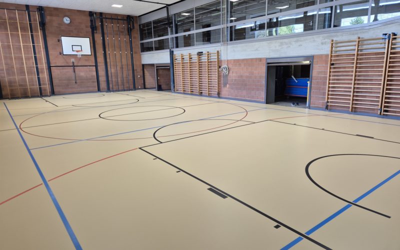 Salle de gymnastique équipée d'un nouveau sol sportif ProtecSport SP 40 beige, avec un marquage noir, bleu et rouge