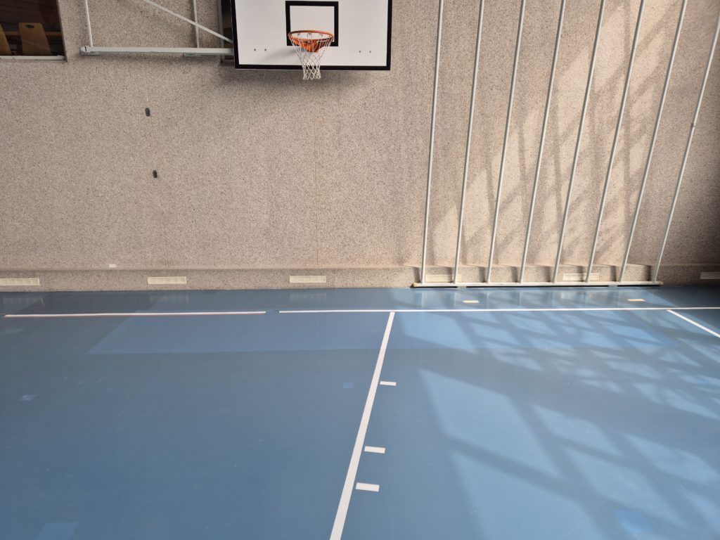 Zone de sol sportif entièrement refaite au pied du mur après un dégât d'eau dans la sous-construction en bois